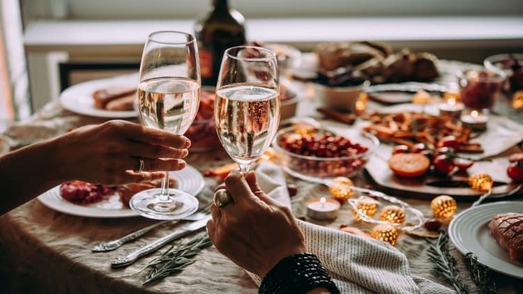 Two people rasising glasses with a decorated table, full of food behind them