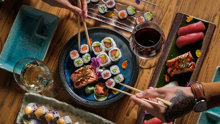 A table full of sushi and a glass of wine